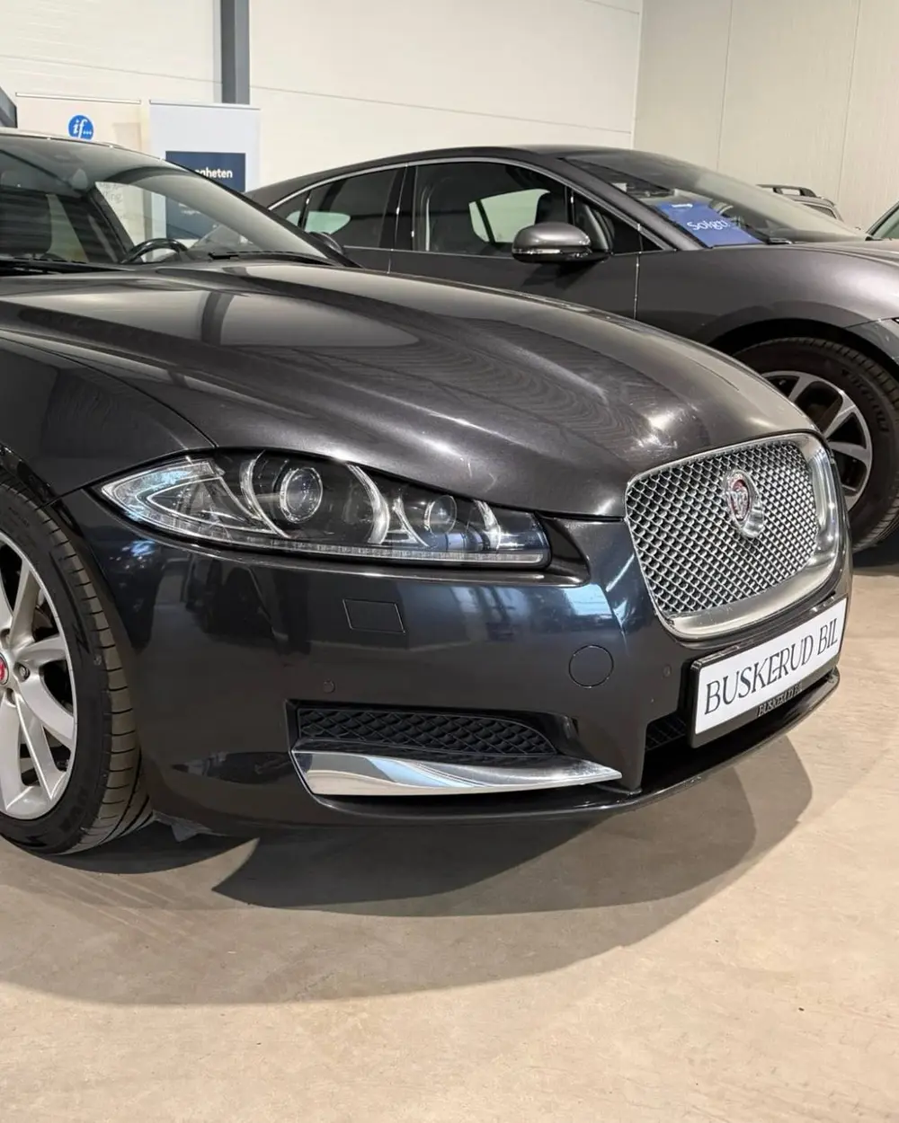 Fronten på en mørkegrå Jaguar XF Sportbrake i hallen til Buskerud Bil